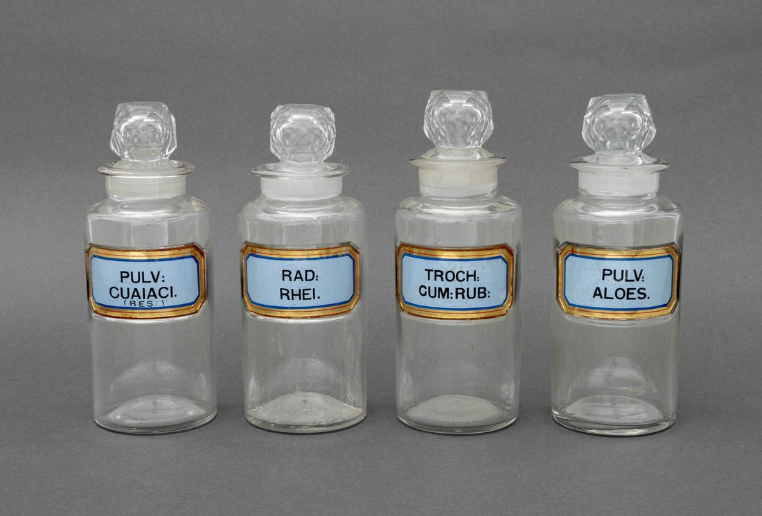 Vintage Glass Apothecary Bottles, 4: Set of Four Vintage Glass Apothecary Bottles, with gilt and blue labels reading: "Troch: Cum: Rub:", "Rad: Rhei.", "Pulv: Aloes.", and "Pulv: Cuaiaci. (Res:)". Each: 8.25" H x 3" Diameter.