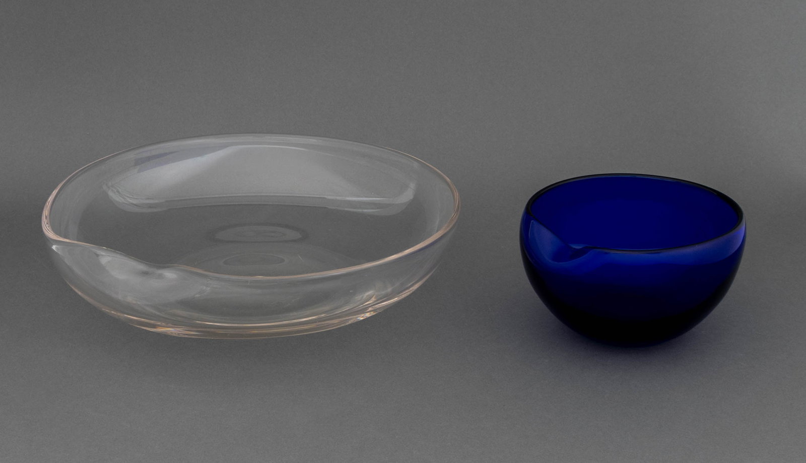 Elsa Peretti for Tiffany & Co. Thumbprint Bowls, 2: Elsa Peretti (Italian, 1940-2021) for Tiffany and Company Two "Thumbprint" Bowls, one fruit bowl in cobalt blue glass and a centerpiece bowl in colorless glass, both marked "Elsa Peretti for Tiffany