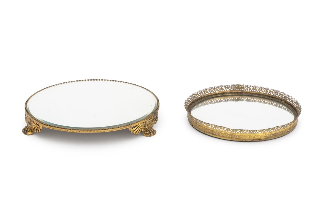 Hollywood Regency Brass Mirrored Vanity Trays, 2: Group of Two Hollywood Regency Brass Mirrored Vanity Trays, one with filigree frame, the other on tripod paw feet and with beveled glass. Larger: 9.75" Diameter x 1.5" D. Provenance: From a New York C