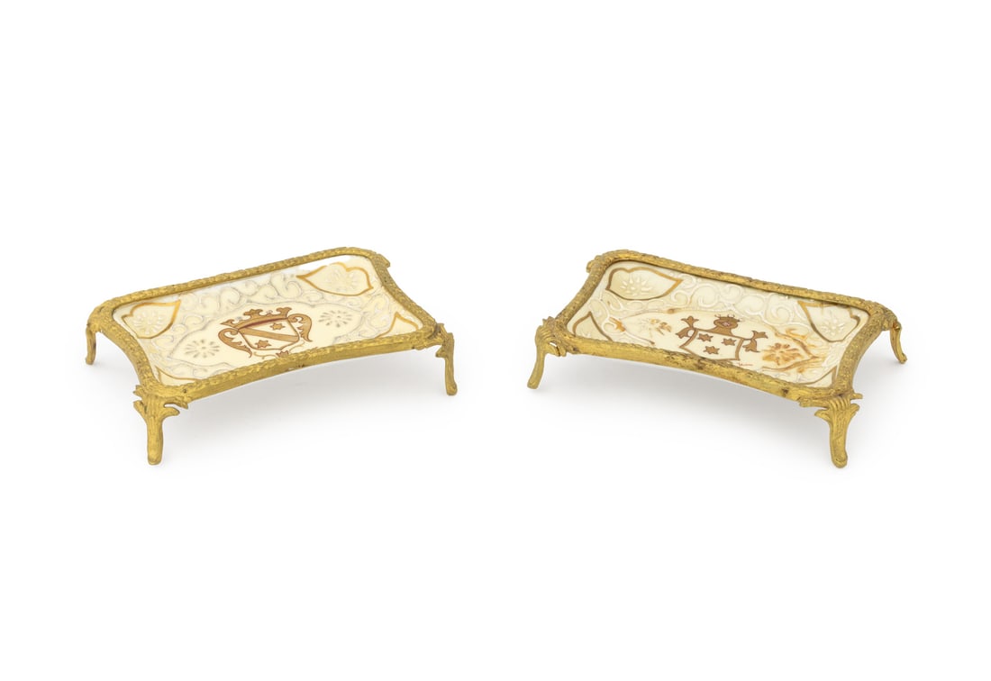 French Gilt Metal and Porcelain Trinket Dishes, 2: Group of Two French Gilt Metal and Porcelain Trinket Dish, footed tray, centered by armorials, each signed "Jean" lower right, marked "France" underside. 1.25" H x 5.5" W x 3.75" D. Provenance: From