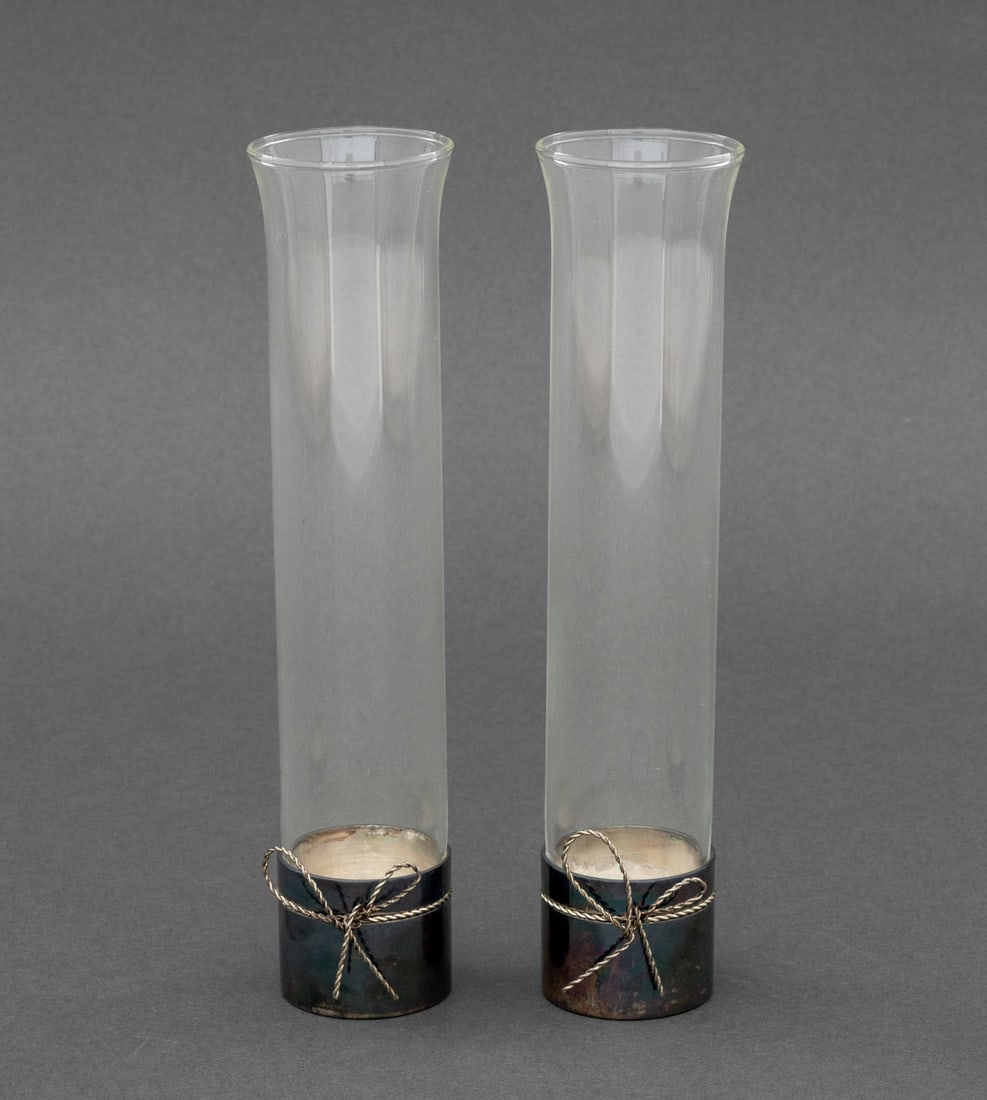 Vera Wang "Love Knots" Bud Vases, Pair: Pair of Vera Wang "Love Knots" Bud Vases, cylindrical forms in silver plate and glass, each marked to underside. 7.5" H x 1.75" Diameter. Provenance: From a 45 Sutton Place South Estate. Keywords: