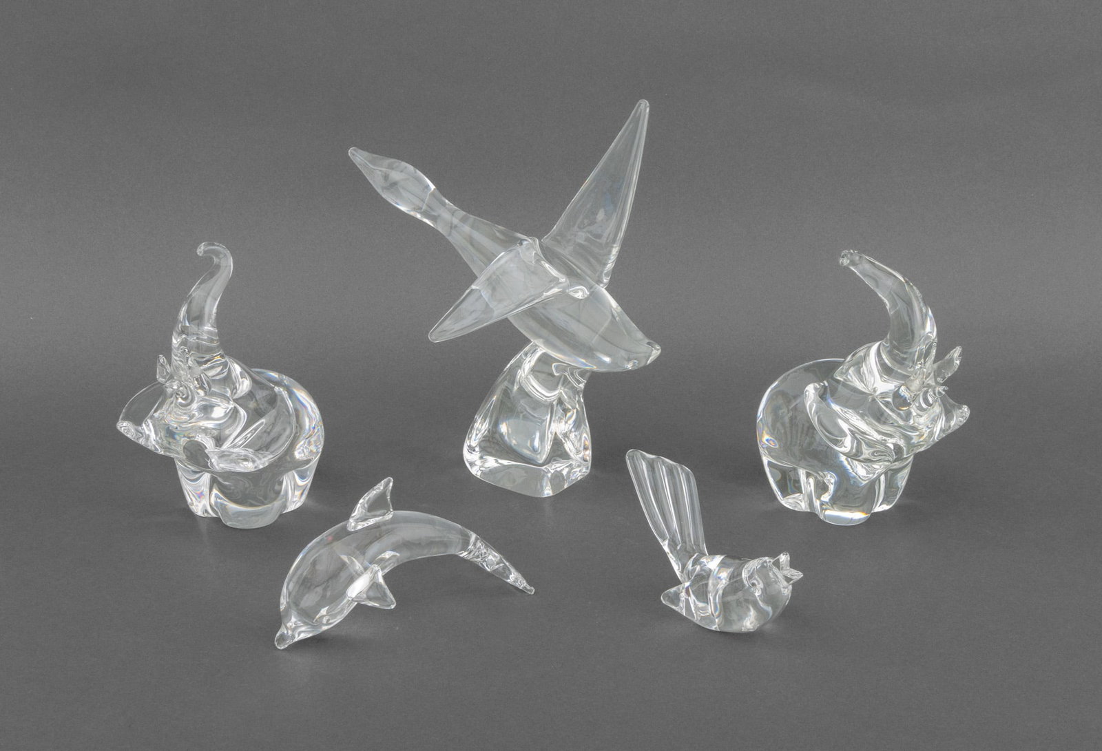 Steuben Glass Animalier Sculptures, 5: Collection of Five Steuben Glass Animalier Sculptures, all marked to underside and comprising: a pair of elephants, a goose, a songbird, and a dolphin. Largest: 10" H x 10" W x 4.25" D. Provenance: