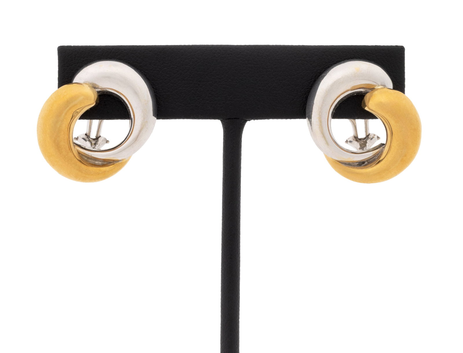 Interlocking Circle Form Two-Tone Gold Earrings: Pair of Interlocking Circle Design 18K White Gold and 18K Yellow Gold Earrings, designed as 18K white gold and 18K yellow gold half circles interlocking, worn as clip-ons with omega backs and pads. Go