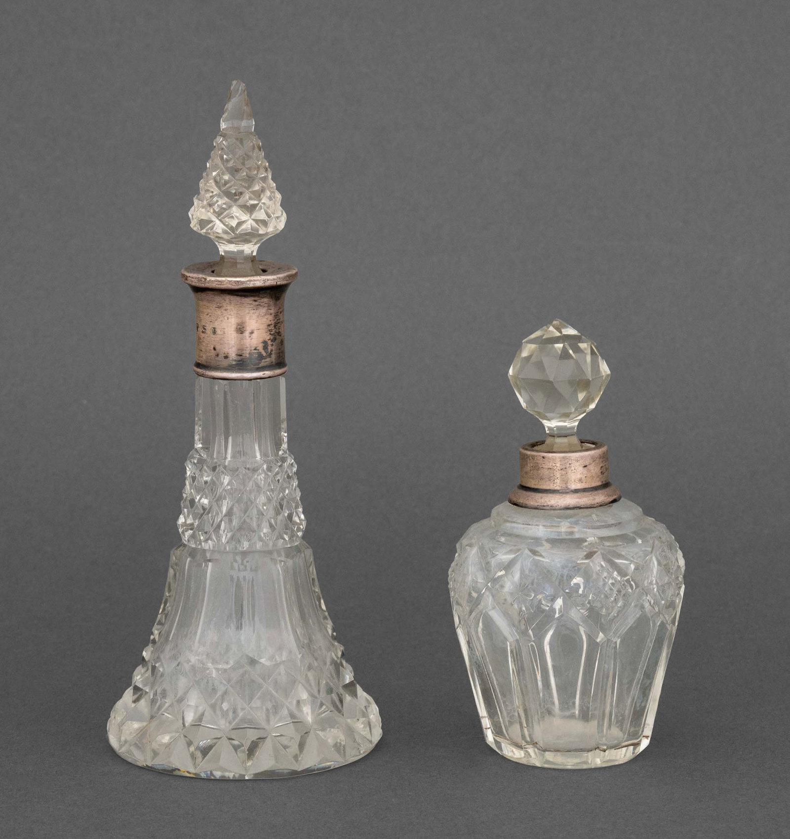 Gorham Silver Mounted Cut Crystal Perfume Bottles: Two Gorham Silver Mounted Cut Crystal Perfume Bottles, each marked to neck. Taller: 7" H x 3" Diameter. Provenance: A Sutton Place Collection. Keywords: Designer, American Silver, Silversmith, Antique