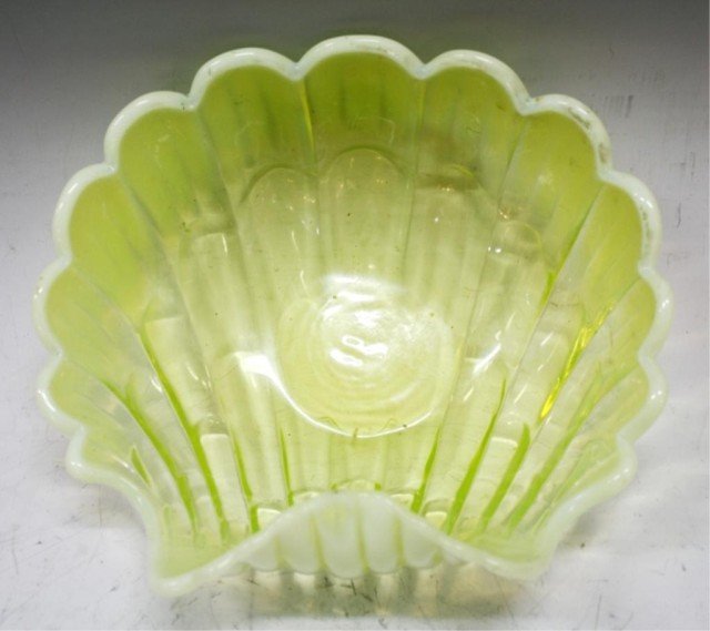 Large Vaseline Glass Seashell Bowl: A large yellow / green vaseline glass bowl in seashell form; unmarked. Dimensions: 5-1/2" H x 11-1/2" L x 9-1/2" W