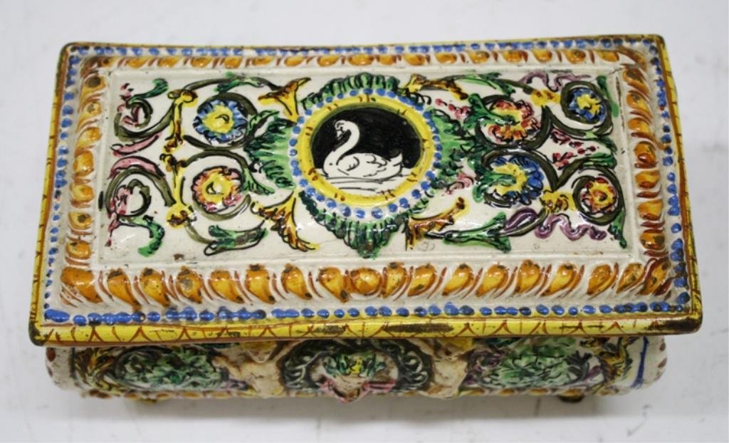 Antique Covered Footed Jewelry Box w/ Cherubs: A vintage ceramic footed jewelry box with lid and yellow, blue, green, and pink floral, cherub, and swan motifs on off-white ground, possibly Italian; unmarked. Dimensions: 3-1/4" H x 6-5/8" L x 3-3/8