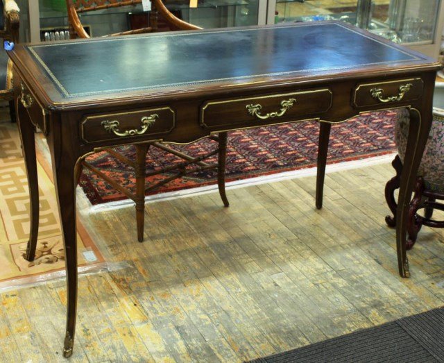 Louis XV-Form Bureau Plat, 20th C.: The walnut desk with gilt-stamped black leather writing surface, painted gilt accents, ormolu drawer handles, cabriole legs ending in ormolu hoofed feet, false drawers on both case sides and one long 