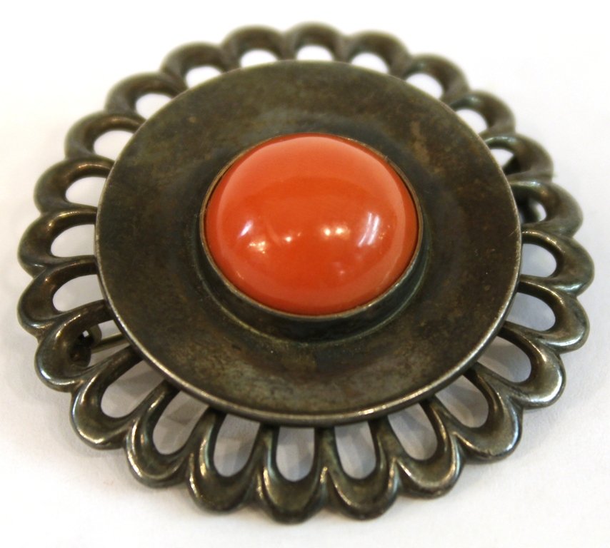 Just Andersen Danish Modern Silver Brooch: Sterling silver and coral, the circular body wreathed by openwork "petals" and mounting a silver saucer with a coral cabochon at center, marked underneath "Just A./ Sterling/ Danmark/ 716." 1.5" diame