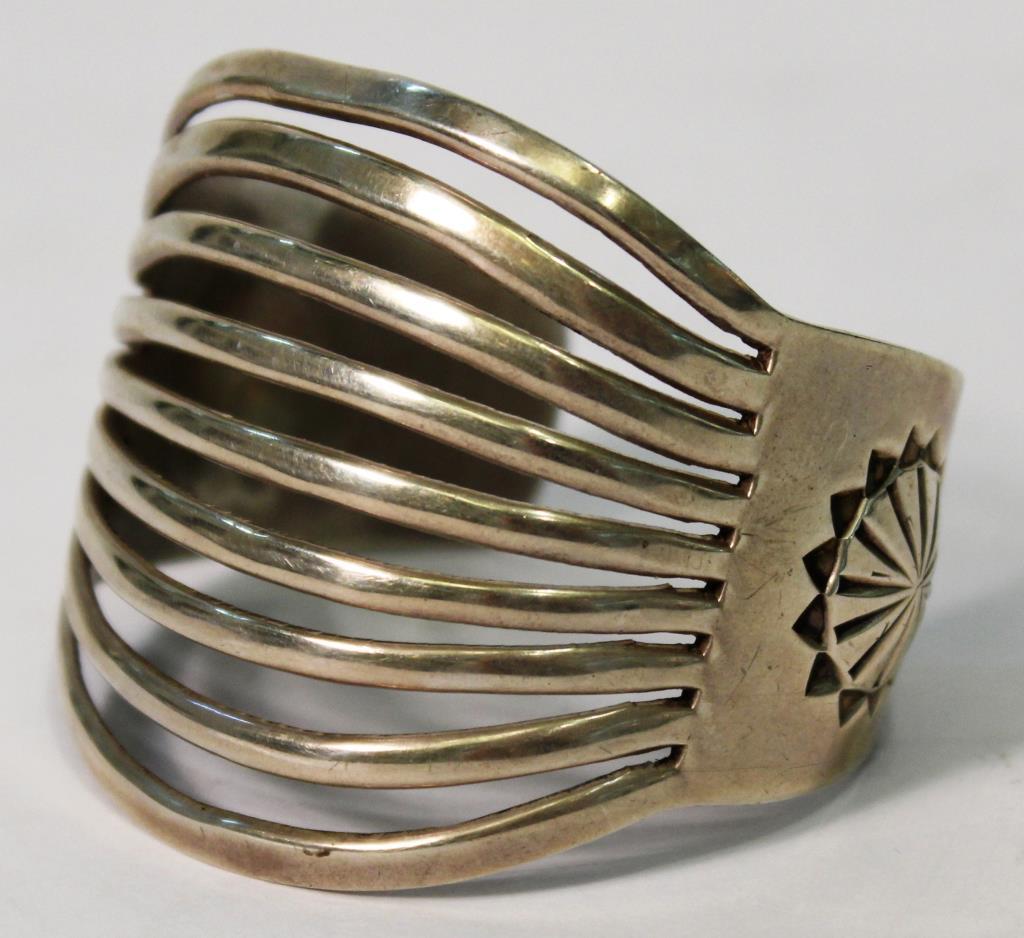 Larson L. Lee Navajo Sterling Cuff: Sterling silver, the band splitting and fanning out into nine narrow ribbons at the top of the wrist, each end also marked with a molded and incised sunflower motif; signed "LLL Sterling" inside. 2.25