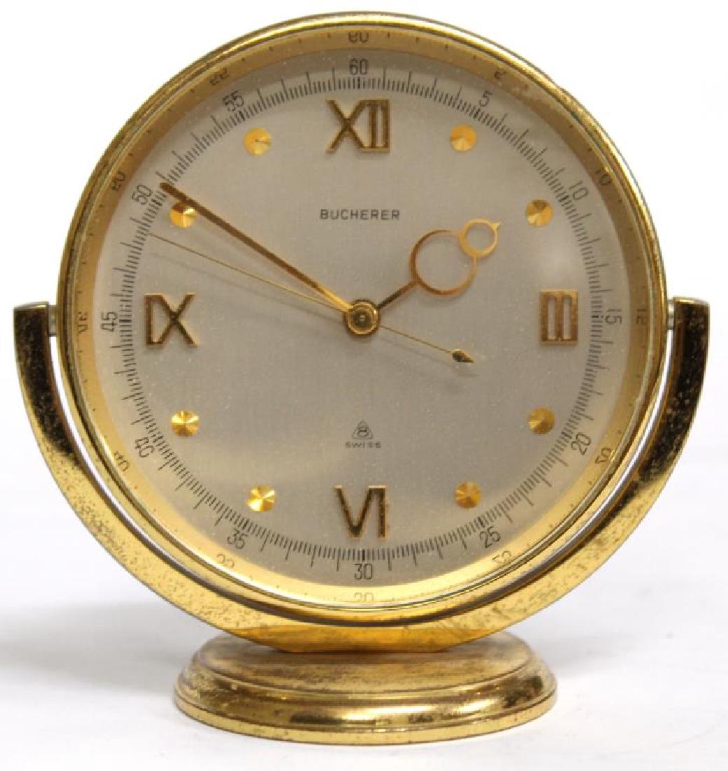 Bucherer Swiss 8-Day Alarm Tabletop Clock: Modernist in form, the gold-tone metal clcok case mounted in a semi-circular frame on a disc base, the white metal face with a mix of Roman numerals and dots. 3.5" H. Wear to gold-tone metal surfaces.
