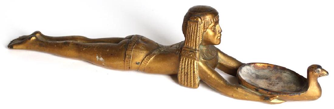 Replica Ancient Egyptian Gold Metal Cosmetic Spoon: In the form of a swimming girl holding onto a goose, the bird's concave body for holding kohl. 13.25" L. Wear to gold paint, burn marks to concave area from use as an incense burner. Property from the