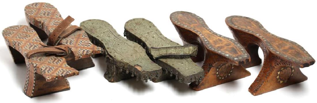 3 Pair of Middle Eastern Pattens: Two pairs with marquetry and mother-of-pearl inlay with incised and carved design, the other with metal repousse with leather strap; women would wear these elevated shoes to keep the hems of their rob