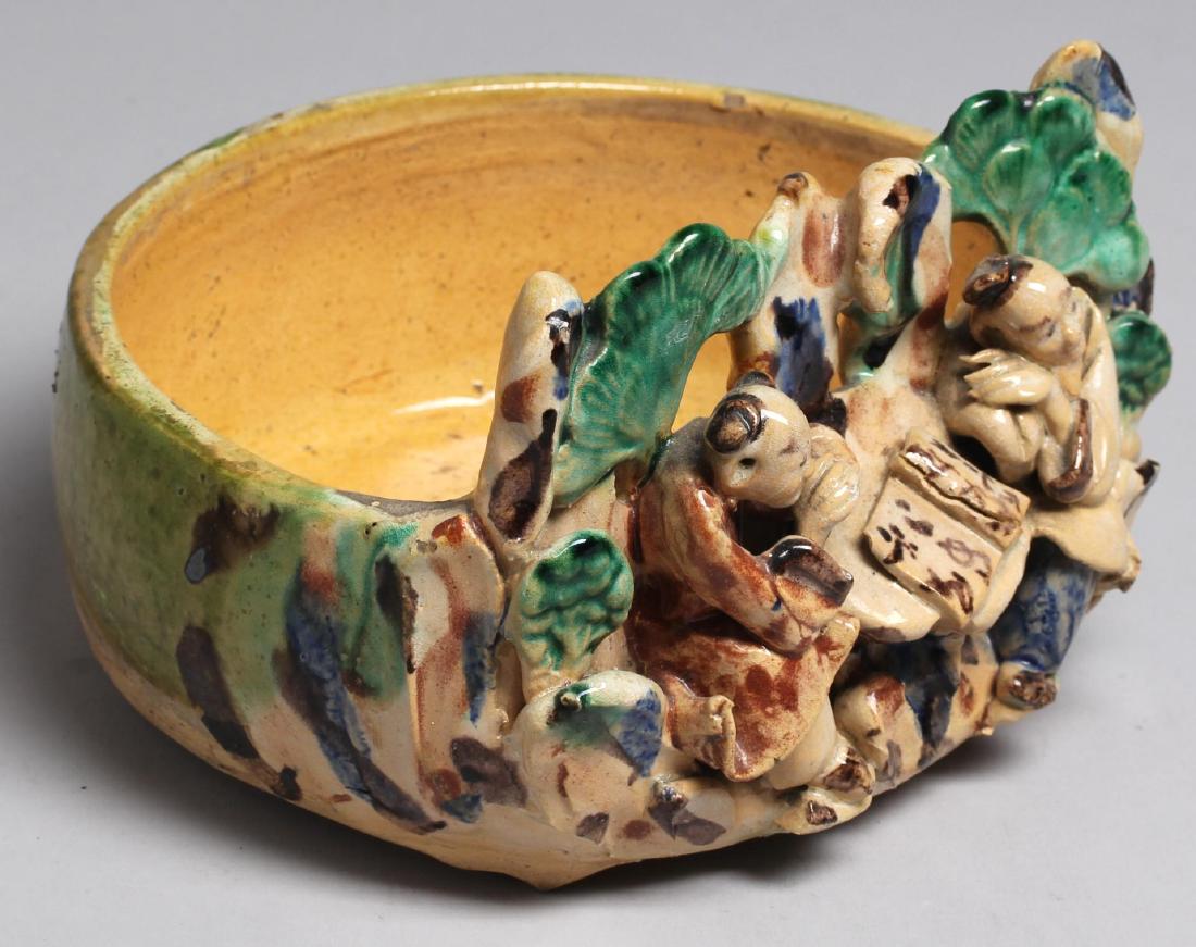 Chinese Glazed Yellow-Ware Planter Dish: Hand-crafted, depicting two Chinese scholars seated at a table amongst trees, drinking and reading a book. 5" H X 7.5" W X 6.5" D.