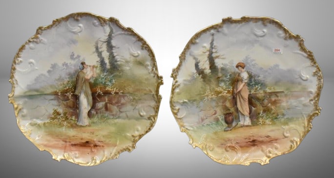 (2) Handpainted porcelain 13.5"d plaques featuring peasant girls scenes: (2) Handpainted porcelain 13.5"d plaques featuring peasant girls scenes;