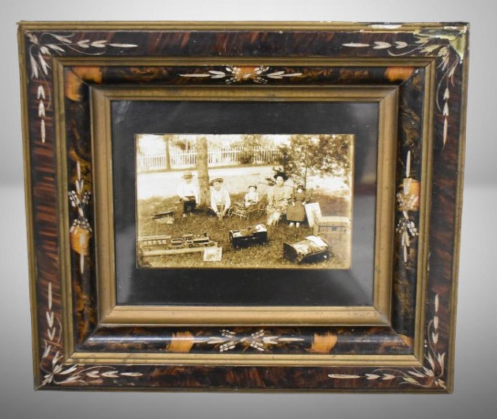 Framed photo of kids sitting outside with their toys, circa 1900: Framed photo of kids sitting outside with their toys, circa 1900; 15"w x 13"h, interesting frame with inlay; few rough spots on frame