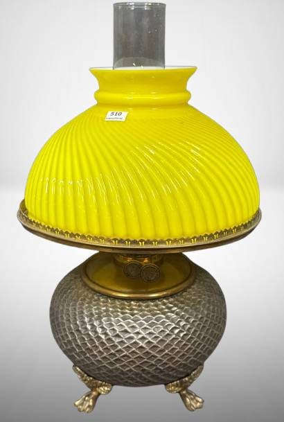 Brass Kerosene Lamp with Yellow Swirl Shade: Brass kerosene lamp featuring a yellow ribbed swirl glass shade and a textured brass base with eagle claw feet. Includes a glass chimney and burner mrkd. C. Parker Co. The shade has a minor no see ? c