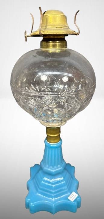 Blue Opaline Kerosene Lamp with Brass Fittings: Blue opaline kerosene lamp featuring a molded blue glass base and clear pattern glass font. The brass fitting holds the kerosene burner, complete with mounting brackets. The lamp exhibits an elegant d