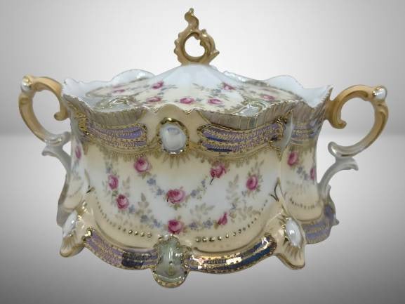 RS Prussia Ribbon and Jewel Mold Cracker Jar: RS Prussia Ribbon and Jewel Mold cracker jar with floral design and gold accents. Features two handles and a lid with ornate finial. RS Prussia red mark in excellent condition with no chips, cracks, o