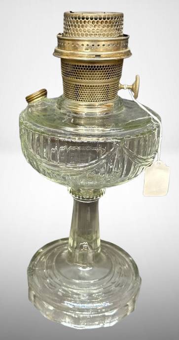 Aladdin Lincoln Drape Oil Lamp with Brass Burner: Aladdin tall "Lincoln Drape" clear glass oil lamp with brass burner assembly and wick knob marked "Mantle Lamp Co. Aladdin." The lamp base exhibits the signature draped glass design. Approximate heigh