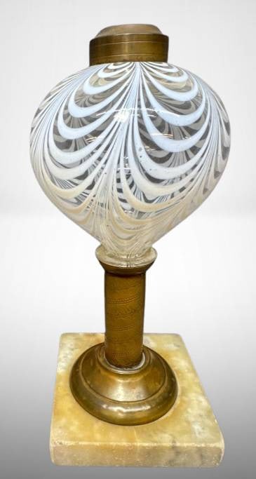 White Opalescent Drapery Kerosene Lamp Base: White opalescent on clear glass Drapery pattern kerosene lamp base mounted on a marble square plinth. Features a brass neck and top fixture. The opalescent glass globe showcases a swirling Drapery pat