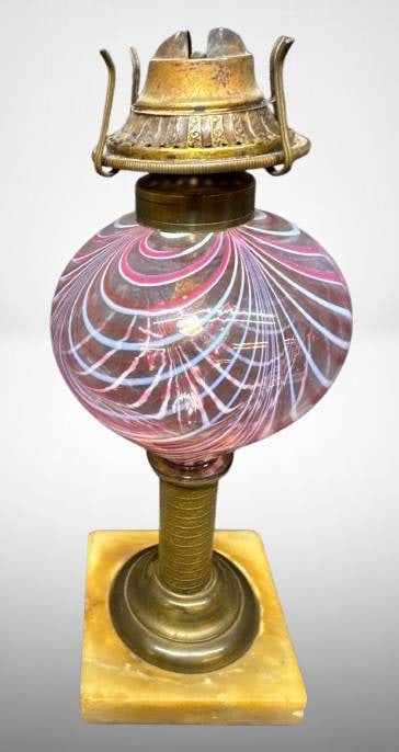 Brass Oil Lamp with Swirled Glass Base: A brass oil lamp featuring a swirled pink and blue glass reservoir. The lamp rests on a square alabaster base and includes ornate detailing on the brass components. Measures approximately 11 inches in