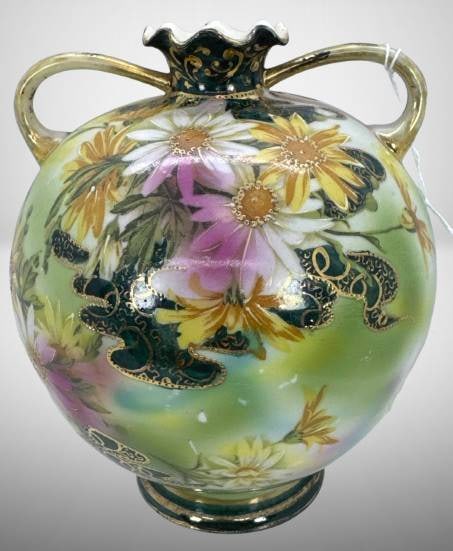Hand-Painted Nippon Floral Vase with Handles: Hand-painted Nippon porcelain 6.5" vase with dual gold handles and a flared, decorative rim. Features floral motifs and lush green, pink, and yellow hues accented by gold detailing. Marked with Nippon