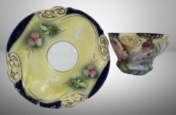 Prov Saxe/ES Germany Cup and Saucer Set: Mrkd. Prov Saxe/ES Germany porcelain cup and saucer set featuring hand-painted floral and portrait motifs. The cup and saucer display intricate gold detailing on vibrant multicolored backgrounds with