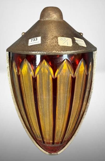 Art Deco Style Wall Sconce with Glass Shade: Art Deco style wall sconce featuring a multi-colored glass shade in red and yellow tones, housed in a metal frame. The glass has a chip along the right edge. Metal frame shows signs of wear. Approxima