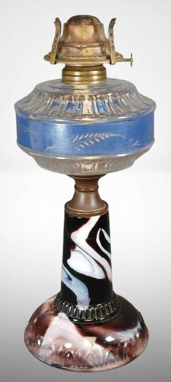 Glass Kerosene Lamp with Painted Base: Glass kerosene lamp with a decorative marbled glass base and blue-painted glass midsection featuring a fern design. The burner appears brass. A chip is noted on the base at the bottom edge as shown in