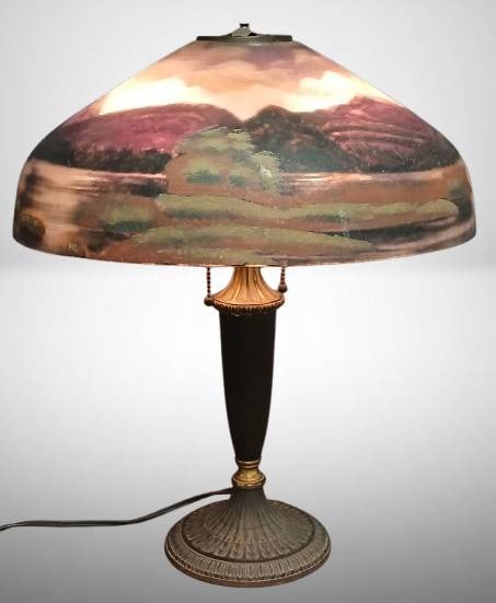 Reverse-Painted Table Lamp, PLB & G Mark: A reverse-painted table lamp featuring a scenic glass shade with landscape motifs. The brass and metal base has decorative detailing, and the lamp exhibits dual pull chains for operation. Base is mark
