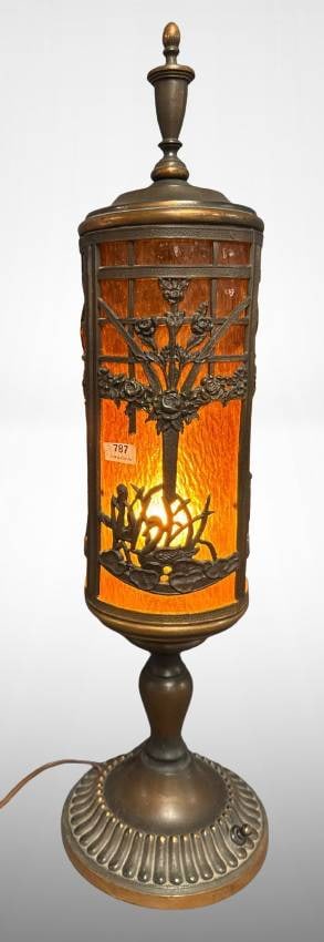 Brass and Amber Glass Table Lamp: Brass and amber glass 23" tall table lamp featuring intricate tree and floral motifs in metal overlay. Cylinder-shape design with amber-colored glass shade, mounted on a detailed brass base. Functiona