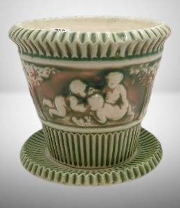 Roseville Donatello 580-5" Flower Pot and Saucer: Roseville Pottery Donatello pattern flower pot with matching saucer, model 580-5. Features embossed cherubs and trees in green and cream tones. Measures 5 inches tall. Notable for aged surface crazing