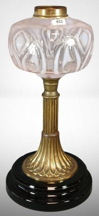 Pink Opalescent Glass and Brass Oil Lamp ?: Table lamp featuring a pink opalescent patterned glass shade and a brass column with fluted design. Mounted on a black base, which has a chip at the bottom. The brass connector and the underside of th