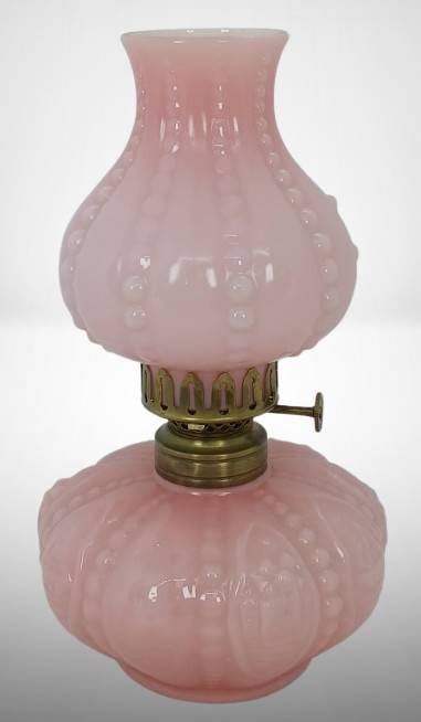 Pink Cased Glass Miniature Oil Lamp with Brass Fittings: Pink cased glass oil lamp with molded patterns of sailboats and windmills on font and brass fittings. The lamp includes a detachable glass chimney and a functional wick mechanism. Minor wear visible,
