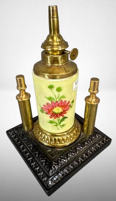 Bradley & Hubbard Cigar Lighter, 1955: Vintage mrkd. Bradley & Hubbard cigar lighter featuring brass construction with hand-painted floral ceramic body on an ornate black metal base. Detachable brass components. Marked and dated 1955. Base