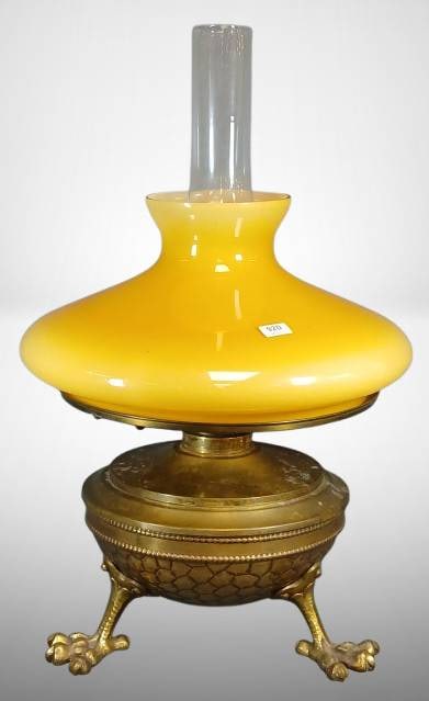 Brass Oil Lamp with Butterscotch Glass Shade: Brass oil lamp featuring a textured body with large claw feet and a honeycomb pattern. Includes a butterscotch glass shade and a chimney. Lamp disassembles for easy maintenance. Overall dimensions app
