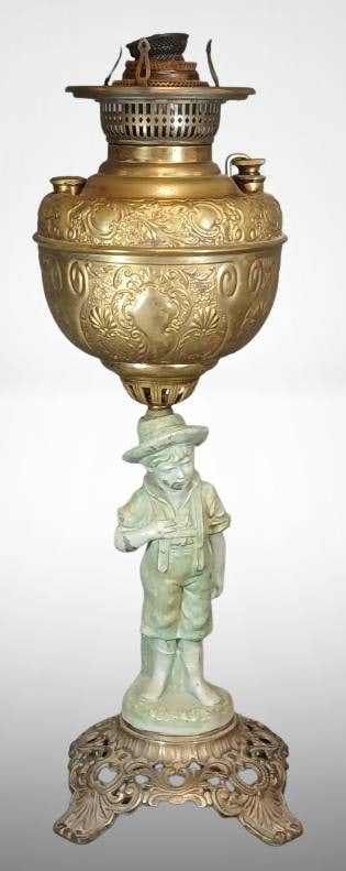Brass Oil Lamp with Boy Figure and Ornate Base: Brass oil lamp featuring an etched brass reservoir mounted above a painted figure of a boy on an ornate cast iron base. The boy figure shows notable finish wear and chipping. Refer to the provided pho