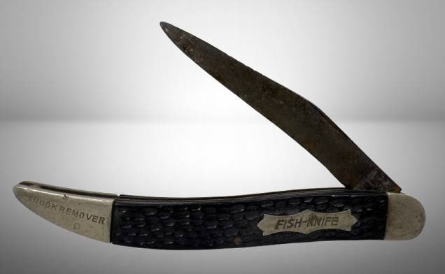 Fish-Knife with Hook Remover: Folding fish-knife with blade and integrated hook remover. Blade shows rust and wear, and the handle features a textured design with 'FISH-KNIFE' engraved on one side. Metal bolster and end cap. Funct