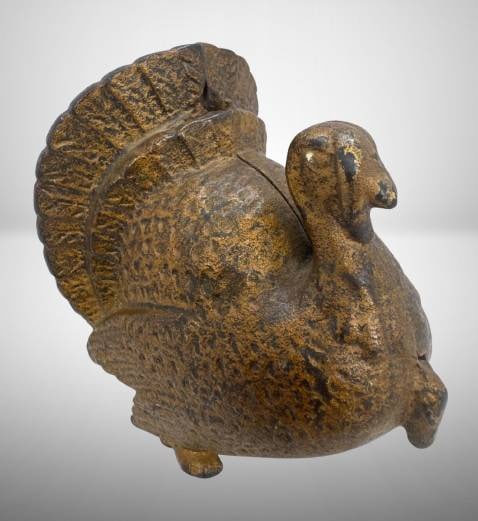 Cast Iron Turkey-Shaped Bank, 4.5" Tall: Cast iron turkey-shaped bank with a detailed feather design. Standing 4.5 inches tall, it features a coin slot and aged patina. Designed to split in two parts, likely for coin retrieval, and secured w