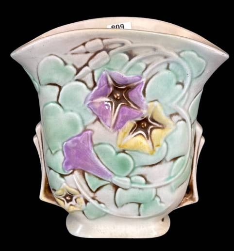 Roseville Pottery Morning Glory Vase, 120-7: This Roseville Pottery 120-7 Morning Glory vase features a delicate floral motif with soft shades of purple, yellow, and green. Measuring 7 inches tall, it has a base chip as shown. A fine example of