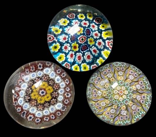 Three Millefiori Glass Paperweights: This lot includes (3) millefiori glass paperweights showcasing colorful floral motifs in vibrant patterns. One is labeled "Perthshire Paperweights," made in Scotland. Each piece exhibits intricate arr