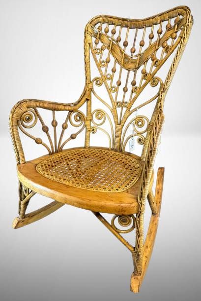Heywood-Wakefield Wicker Rocking Chair: This Heywood-Wakefield wicker rocking chair showcases the craftsmanship of the Gardner, MA-based manufacturer. Bearing its original maker's tag, it features an intricate woven design and a caned seat,