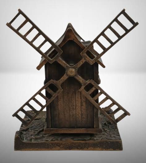 French Bronze Windmill Bank with Moving Sails: A French bronze windmill bank featuring intricate details and functional moving sails. A charming design, likely used as a coin bank. The piece showcases fine craftsmanship, with a secure base and age