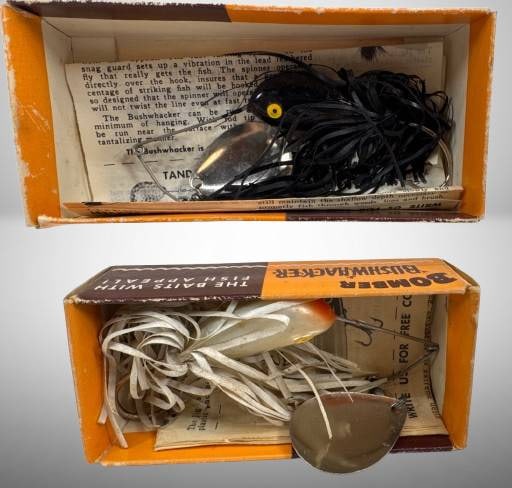 2 Bomber Bushwhacker Fishing Lures: This lot includes two Bomber Bushwhacker fishing lures in original packaging. Both lures, black and white, feature tandem spinners and original documentation. The boxes showcase marketing slogans, evi