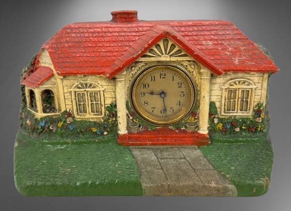 Bungalow House Clock with Red Roof Design: Depicting a charming bungalow with a red roof, this DeLuxe Clock Co. mantel clock features a detailed painted design. Fully functional, it measures approximately 9" in width x 6" tall. Marked on the b