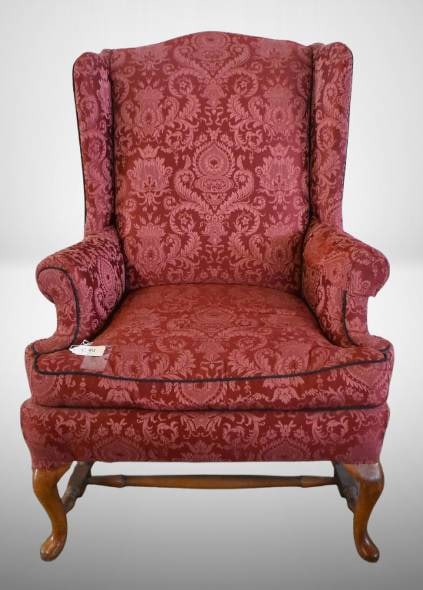 Red Damask Upholstered Wingback Chair: This wingback chair features red damask-patterned upholstery and classic wooden legs with stretcher support. Subtle wear is visible on the edges, adding to its character. A timeless piece for seating