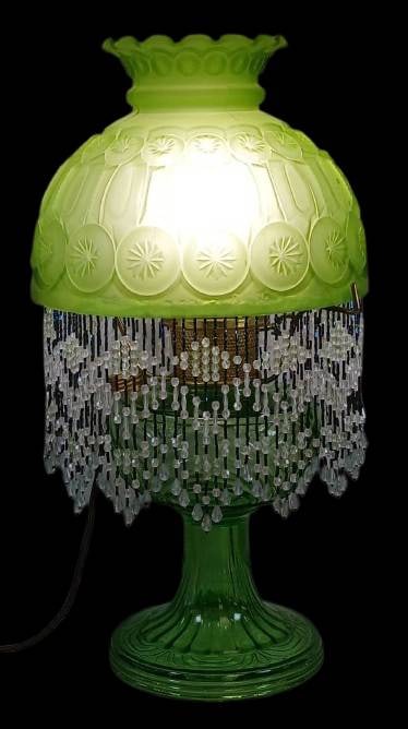 Aladdin Washington Drape Electrified Lamp: Aladdin Washington Drape electrified kerosene lamp featuring a green glass base, paired with a L.E. Smith Moon and Stars frosted green shade with hanging bead fringe. Includes a chimney and cord. 19"