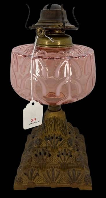 Opalescent Glass Oil Lamp With Decorative Metal Base: This oil lamp features a pink opalescent glass reservoir with a Meander-like pattern and paired with an ornate metal base showcasing intricate patterns. Measures 12" tall. A charming piece for collect