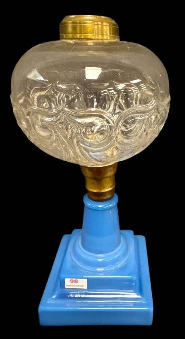 Glass Font Lamp with Blue Glass Base: This lamp features an EAPG clear glass font with an ornate design and a brass fitting atop a vibrant opaque blue milk glass base. Base shows a couple no harm minute chips. A must for collectors or dec