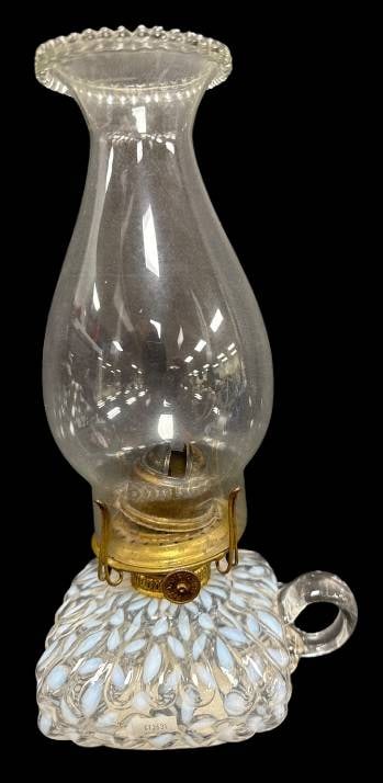 Glass Oil Lamp With Opalescent Base: This glass oil lamp features a decorative opalescent base with textured white and blue accents and a clear glass chimney. The brass burner mechanism adds a classic touch, while the attached handle enh